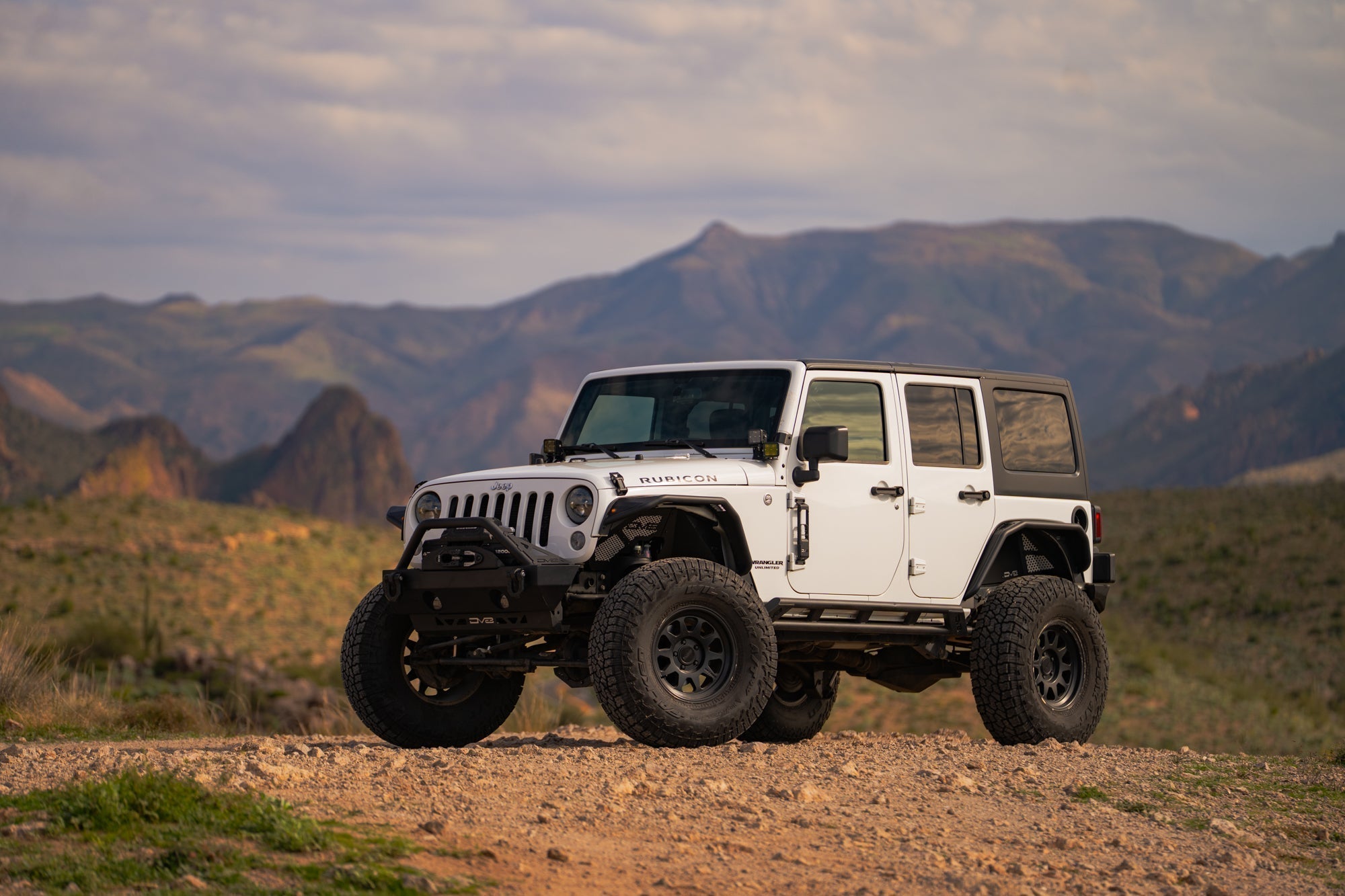 A Jeep JK off-road in the desert with DV8 bumpers.