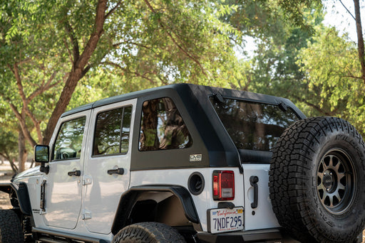 White 2007-2018 Jeep JK 4-Door with DV8 Fastback Hard Top in a forest setting