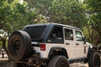 White 2007-2018 Jeep JK 4-Door with DV8 Fastback Hard Top and off road accessories tires in a forest setting