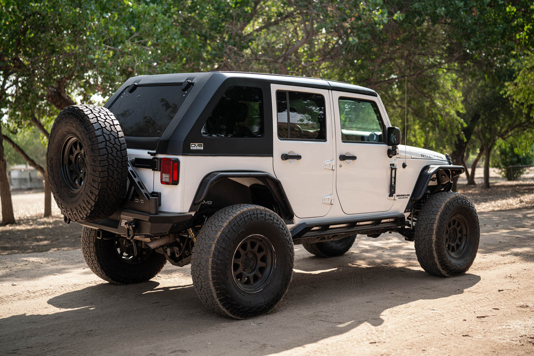 White 2007-2018 Jeep JK 4-Door with DV8 Fastback Hard Top on a dirt road surrounded by trees