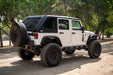 White 2007-2018 Jeep JK 4-Door with DV8 Fastback Hard Top on a dirt road surrounded by trees