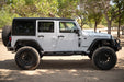White 2007-2018 Jeep JK 4-Door with DV8 Square Back Hard Top parked on a dirt road with trees in the background