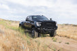 Spec Series Front Bumper for the 2020-2023 GMC Sierra 2500/3500 on a dirt road with grassy landscape and cloudy sky