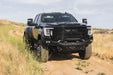 Black 2020-2023 GMC Sierra 2500/3500 with Spec Series Front Bumper on a dirt road in a natural landscape. Optional bull bar installed