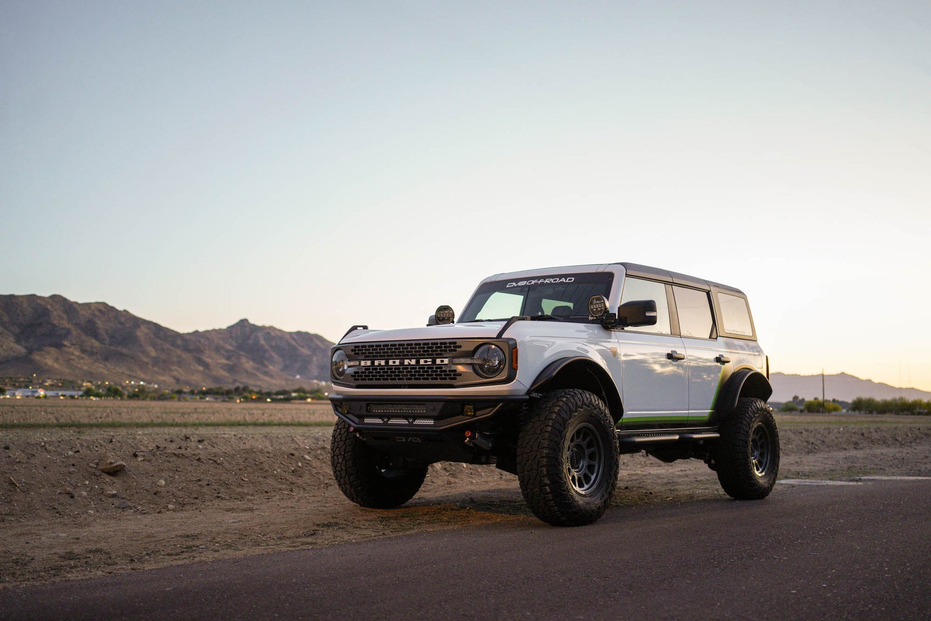 White Ford Bronco SUV on a road with mountains in the background, competition series bumpers.