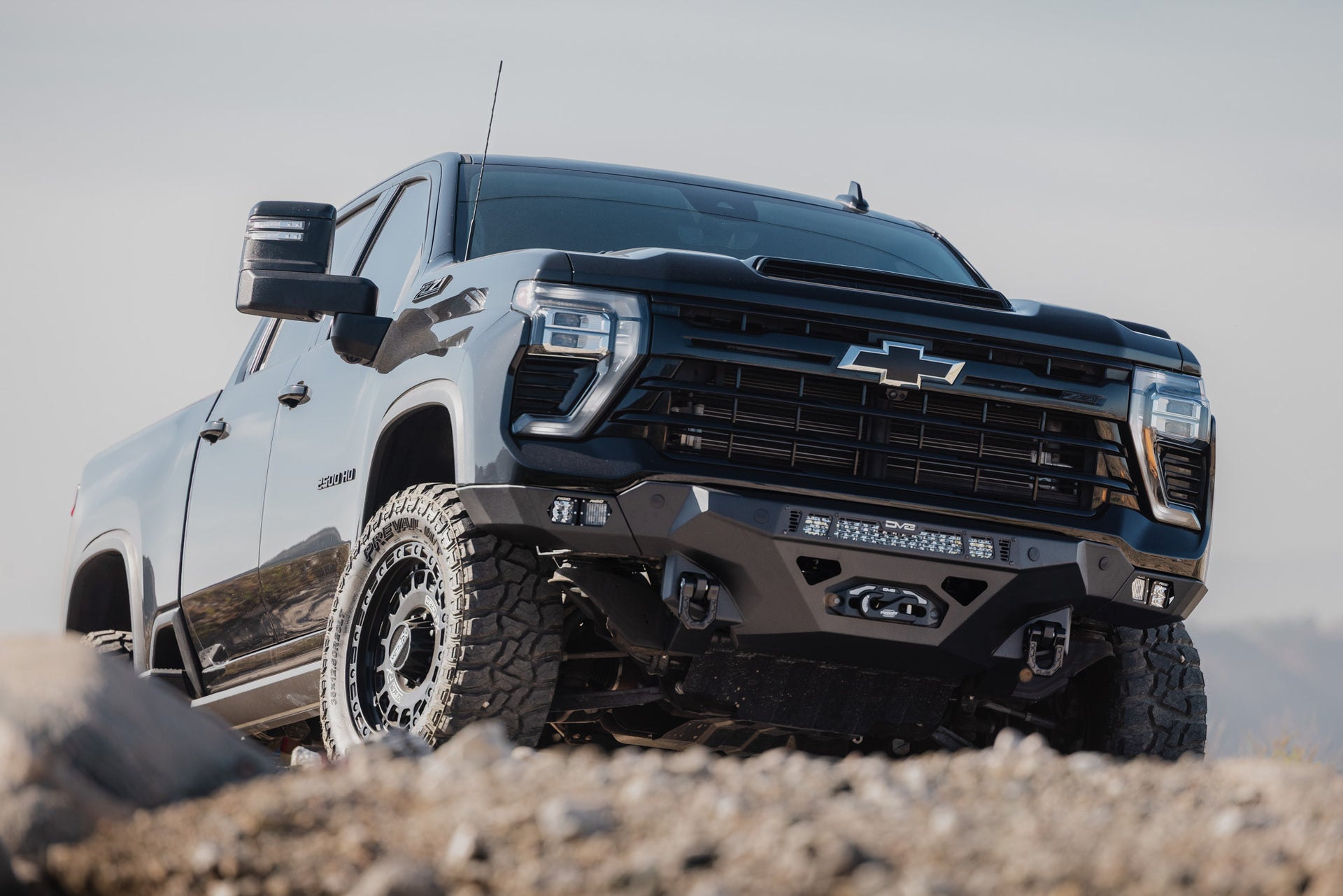 2024-2026 Chevy Silverado 2500/3500 with Spec Series Front Bumper on a rocky terrain with a clear sky.