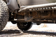 Close-up of a trailing arm skid plate on a dirt road