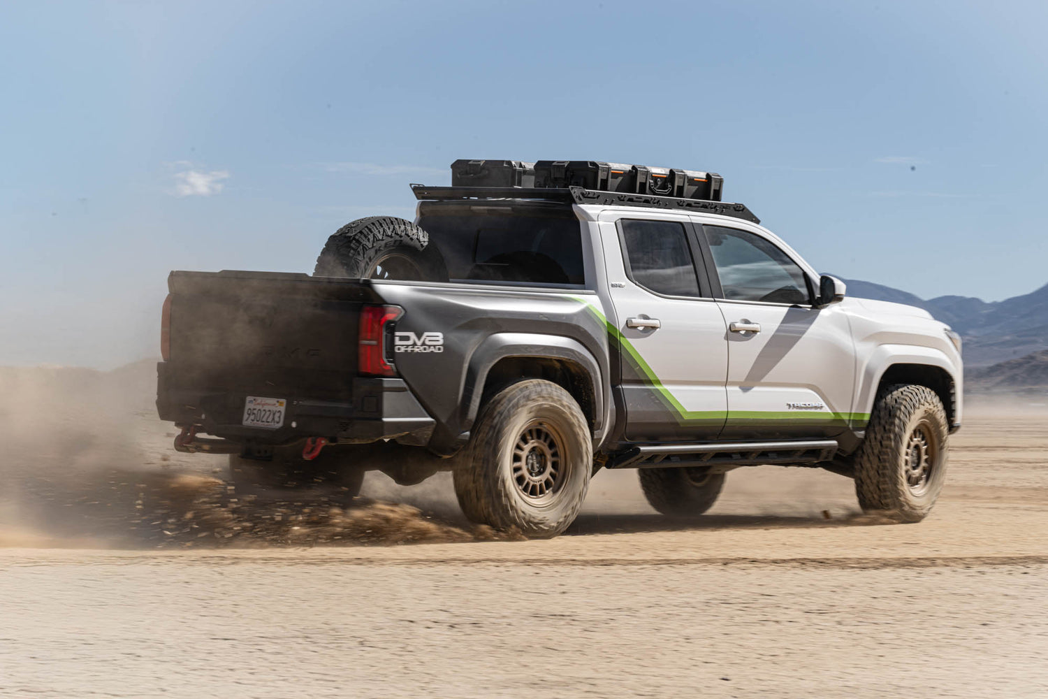 Off-road truck driving on a dirt road with mountains in the background