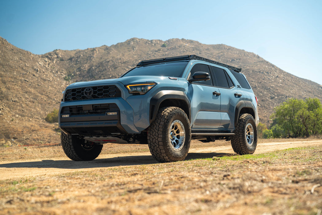 Blue 6th Gen Toyota 4Runner with Roof Rack Light Cutout installed on a dirt road with mountains in the background