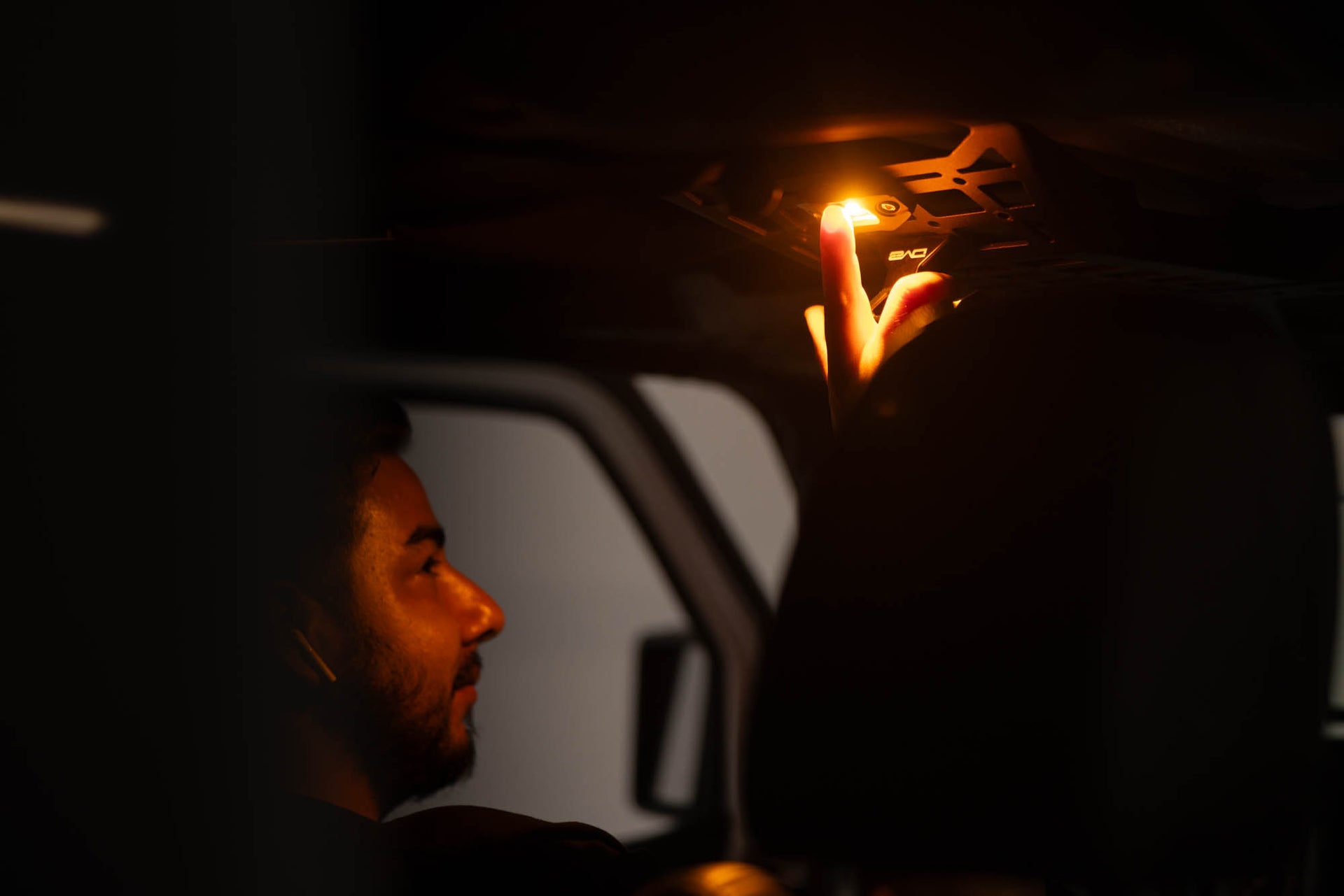 Man pushing on/off button of the Elite White/Amber Push Button Dome Light by DV8 Offroad