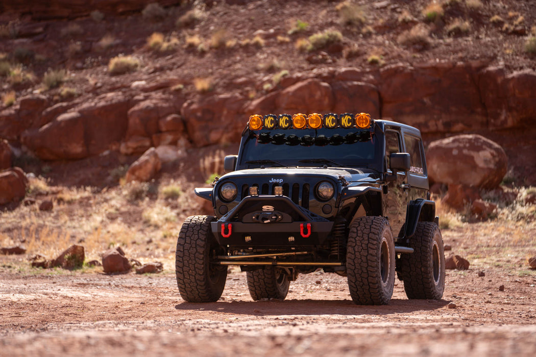 Jeep Wrangler JK in a desert landscape with rocky background, DV8 Offroad bumpers and accessories.