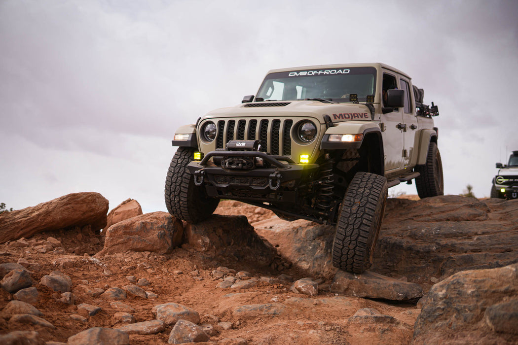 Jeep Gladiator driving on rocky terrain with a cloudy sky.