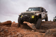 Jeep Gladiator driving on rocky terrain with a cloudy sky.
