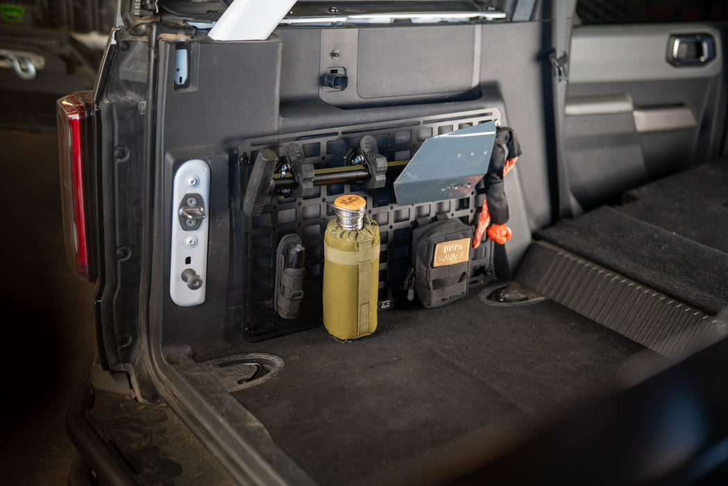 Trunk of a vehicle with Universal Molle Panel equipped with tools and gear.