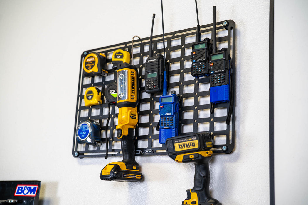 Wall-mounted Universal Molle Panel with various power tools and equipment on a white wall.
