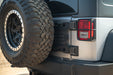 Close-up of a vehicle's rear tire and Jeep Wrangler JK Tailgate Reinforcement Molle Panel on a sunny day.