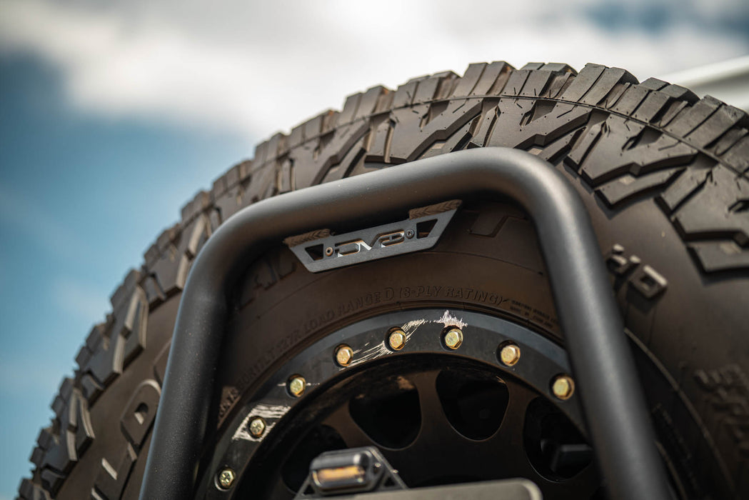 Close-up of a tire with a rugged tread pattern and protective metal guard against a blue sky.