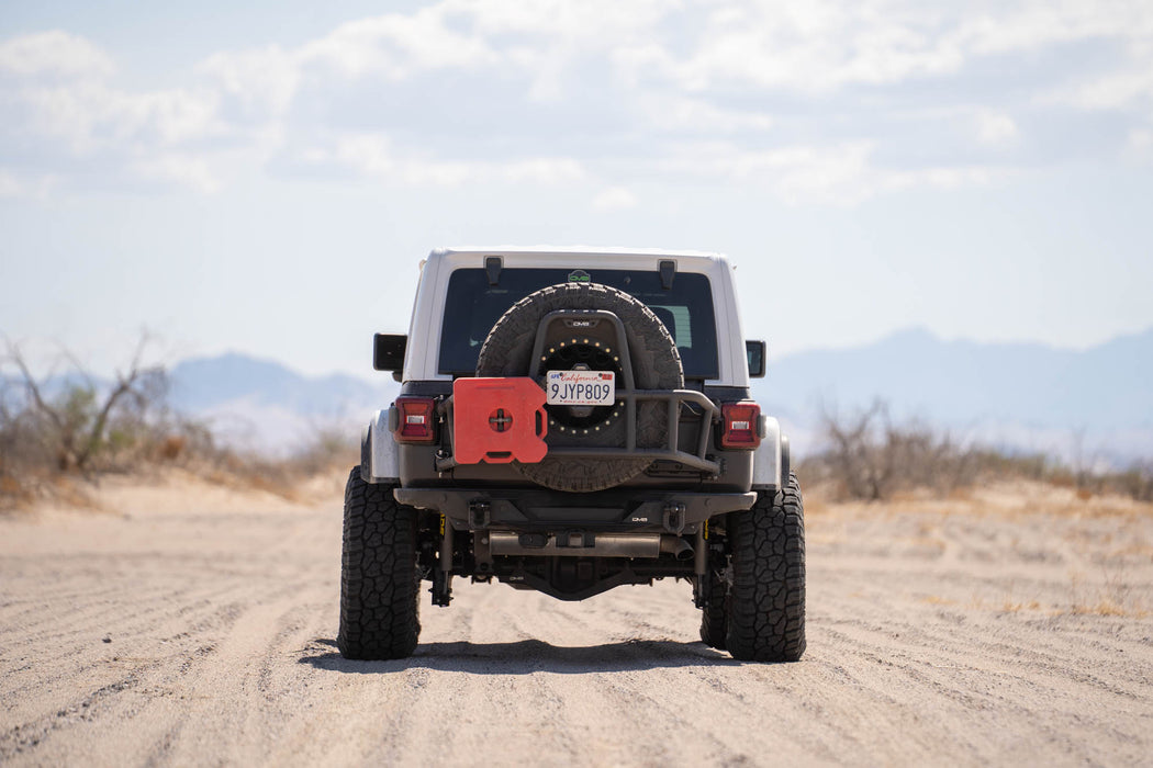 Jeep on a dirt road with a 2018-2025 Jeep Wrangler JL Body Mounted Tire Carrier and Rotopax
