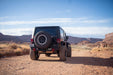 Black off-road Jeep JK on a dirt road with desert landscape and blue sky.