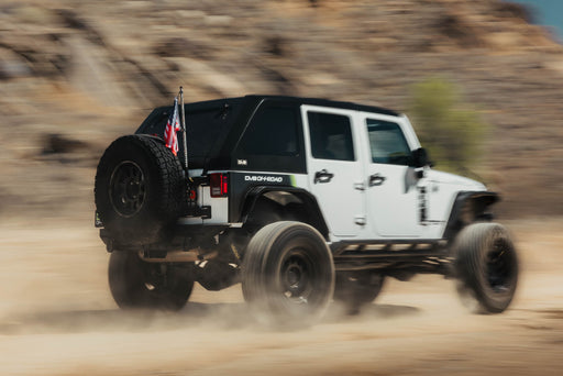 Image of jeep driving in fast motion with Universal Molle Adjustable Antenna & Whip Mount installed for flag off the rear door molle panel