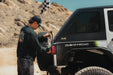 Person using the Universal Molle Adjustable Antenna & Whip Mount to mount flag on vehicle
