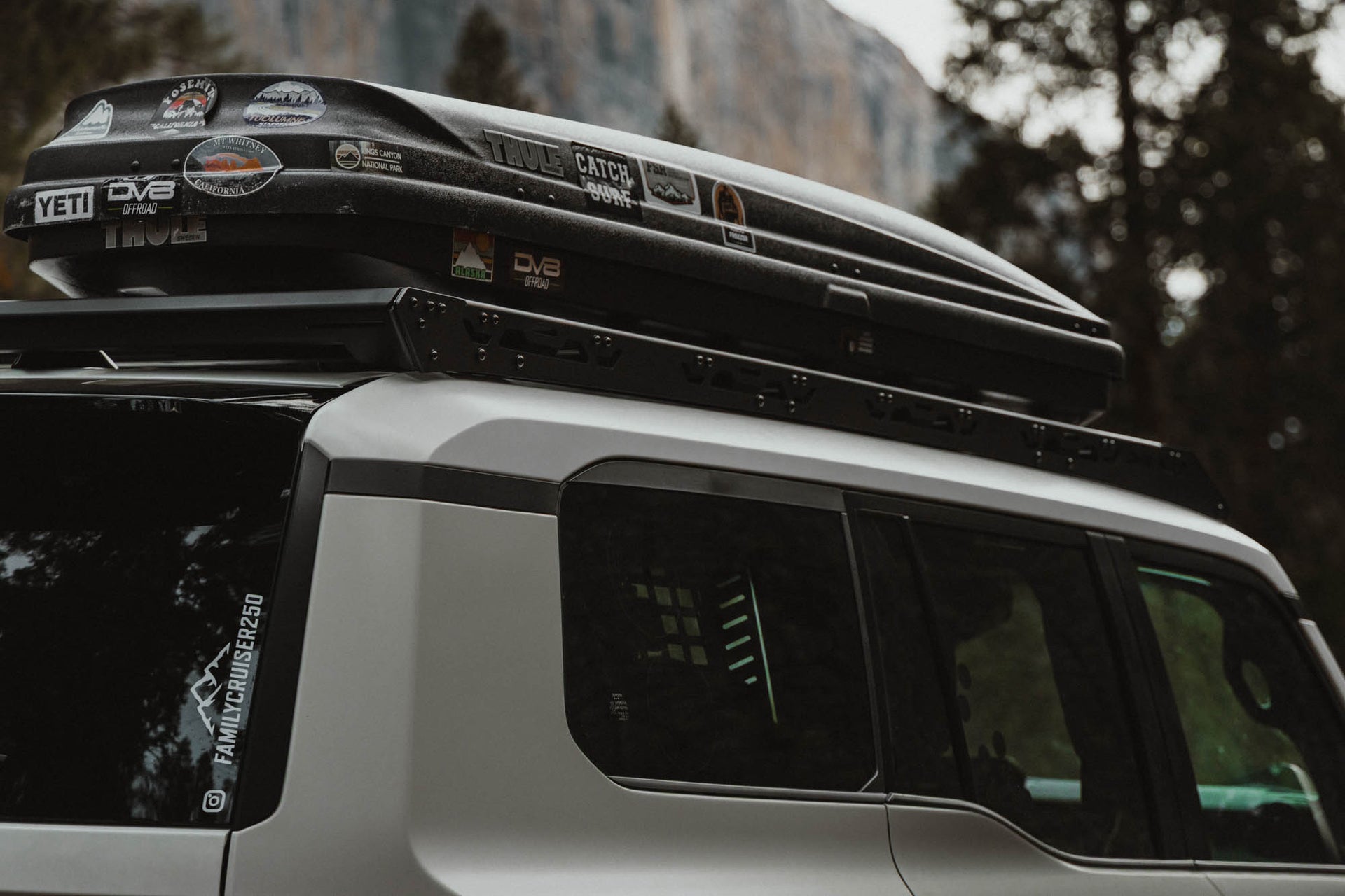 Roof rack system on a vehicle with visible branding against a blurred natural background