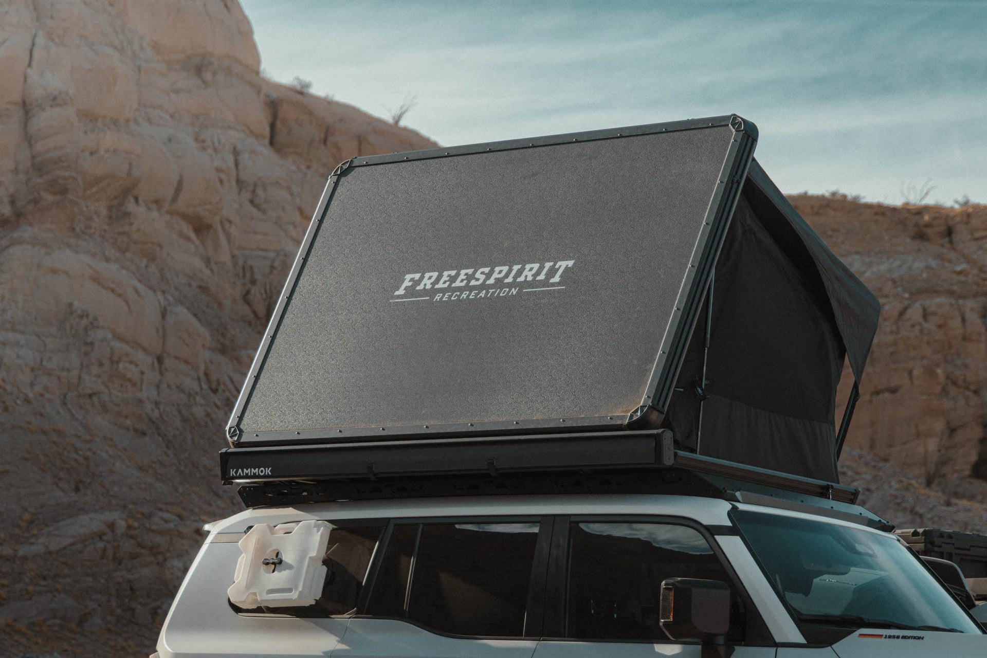 Roof top tent with 'Freespirit Recreation' branding on a vehicle in a desert setting.