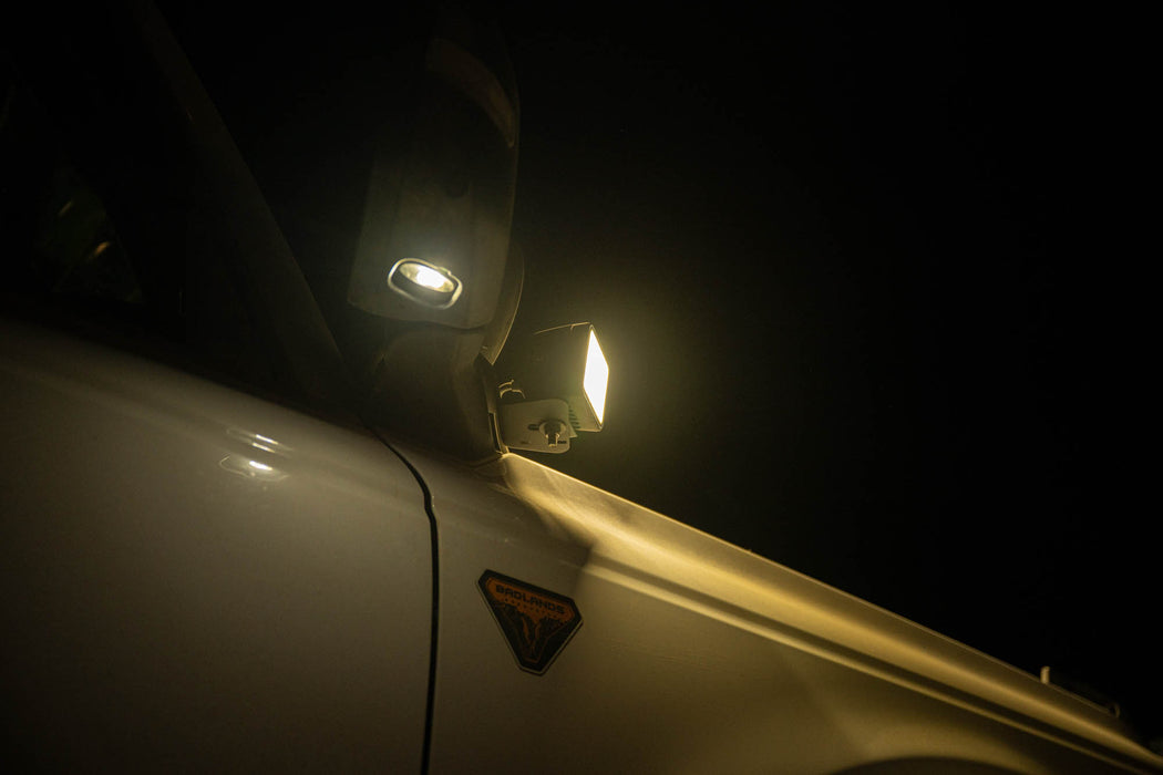 Car side mirror reflecting a bright light against a dark background