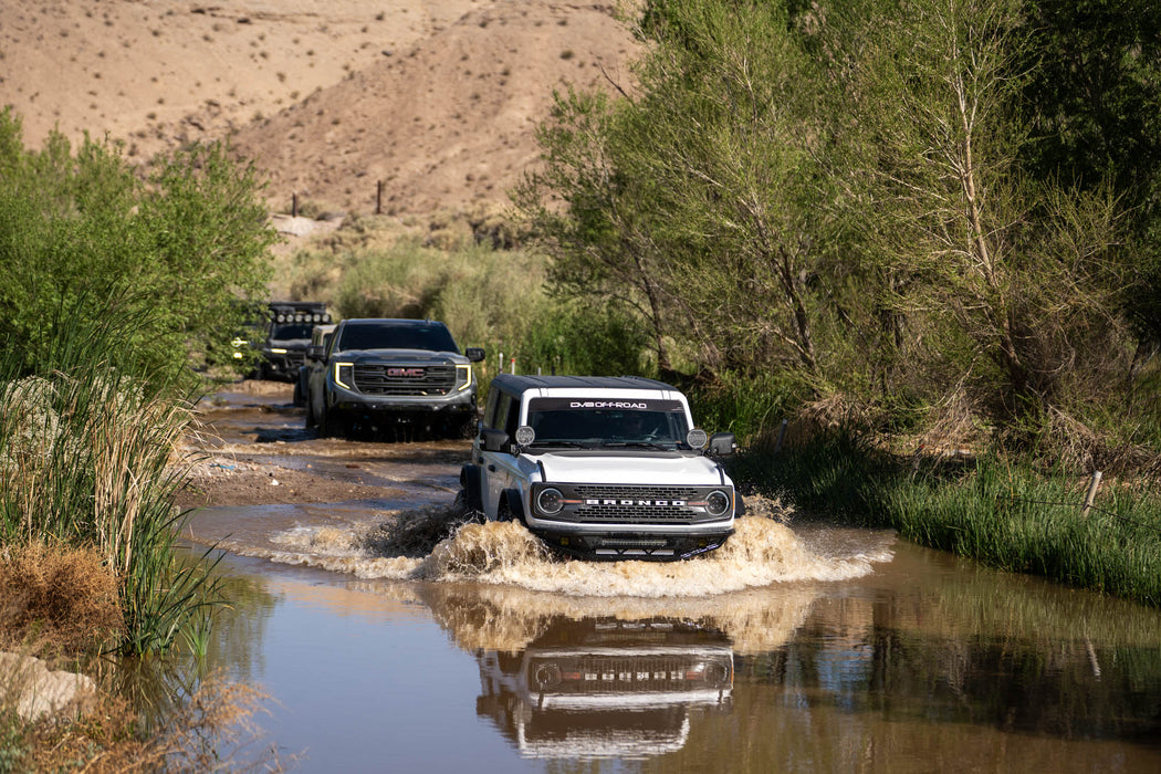 Ford Bronco vehicles driving through a river in a desert setting with the competition series front bumper.