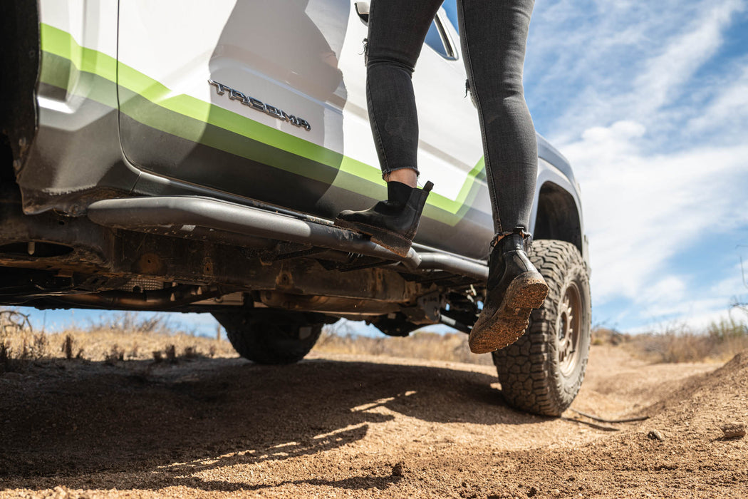 Person stepping onto a vehicle with DV8 off-road Steps on a dirt road